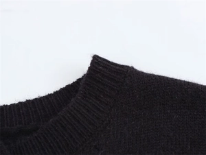 Dettaglio dello scollo rotondo a costine su questo cardigan in maglia nera