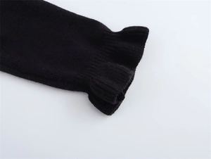 Dettaglio ravvicinato della trama in maglia e polsino a balze del cardigan nero