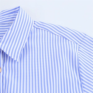 Détail du col et de la couture d'épaule d'une chemise rayée en lin sur fond blanc