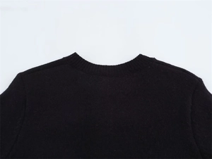 Dettaglio del girocollo e delle cuciture sulla spalla del maglione nero in maglia