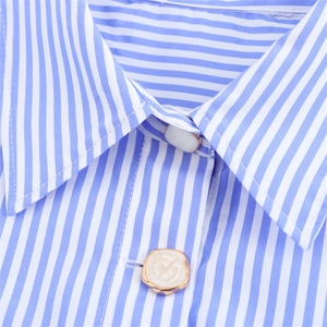 Gros plan du col de chemise à rayures bleues et blanches avec boutons dorés ornés
