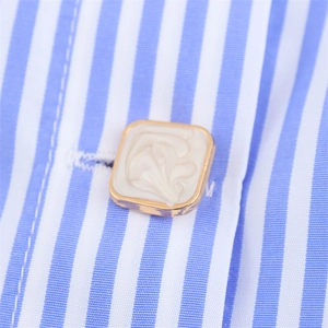 Vue macro d'un bouton doré carré à motif marbre sur une chemise à rayures