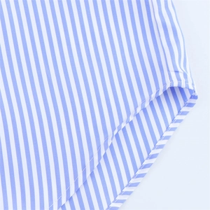 Détail de chemise en lin à rayures bleues et blanches montrant l'ourlet incurvé et les coutures