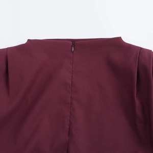 Dettaglio di un top bordeaux scuro con cerniera invisibile e texture del tessuto premium