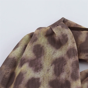 Detailed macro view of tie-dye mesh fabric with brown patterns and precise stitching