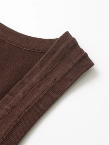 Detail of high-density flat knit fabric and rib stitching on dark brown top