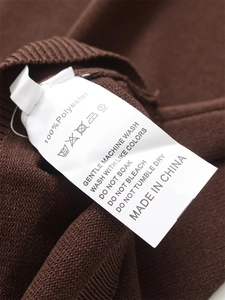 Macro view of 100% polyester fabric care label and washing instructions on brown knitwear