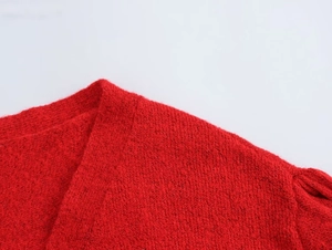 Nahaufnahme einer roten Strickjacke mit V-Ausschnitt und 3D-Blumendetails am Kragen