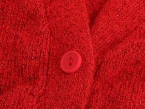 Detailansicht der roten Strickjacke mit flauschiger Textur und passendem mattem Knopf