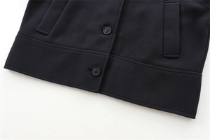 Detailed close-up of dark wool blend coat hem showing buttons and pocket stitching