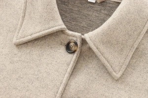 Close-up of oatmeal wool coat detailing lapel collar and textured brown button