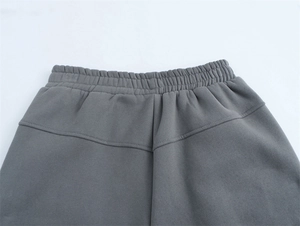 Dettaglio dei pantaloni sportivi grigio scuro con vita elastica e cuciture premium