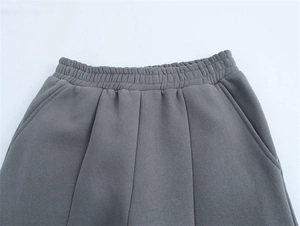 Dettaglio di pantaloni della tuta grigio scuro con vita elastica e tasche laterali