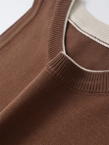 Detailaufnahme der braunen Strickweste mit cremefarbener Paspelierung und feiner Textur
