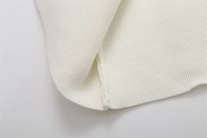 Dettaglio macro della trama in maglia bianca di qualità e cuciture precise sul bordo
