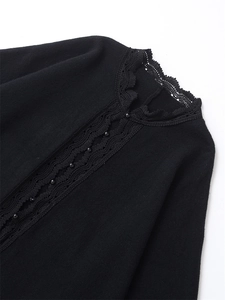 Detail of delicate black lace trim and bead accents on a loose knit cardigan