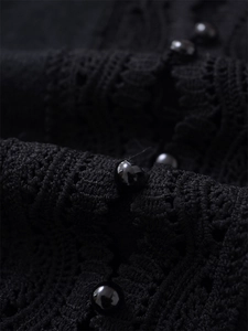Close-up of intricate black lace knit fabric featuring polished round buttons detail