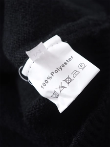 Detail view of garment care label and M size tag on black knitted fabric