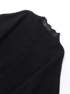 Detailed close-up of delicate black lace trim on the neckline of a knit cardigan