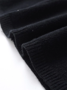 Close-up detail of black knitted fabric with ribbed cuffs and refined stitching texture
