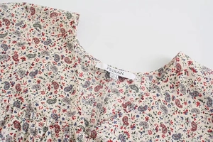 Dettaglio della camicetta con scollo a V, motivo paisley elegante e etichetta marca