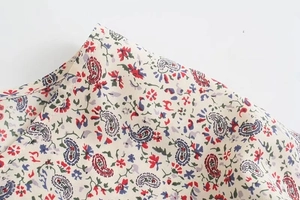 Dettaglio della stampa floreale paisley su tessuto bianco avorio con cuciture fini