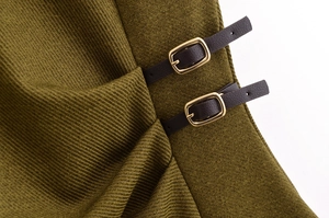 Detailed close-up of olive green twill fabric with black leather straps and gold buckles