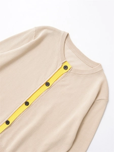 Détail d'un cardigan en maille beige avec bordure jaune et boutons noirs