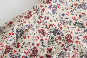 Dettaglio del tessuto con stampa paisley e floreale con delicate cuciture a pieghe