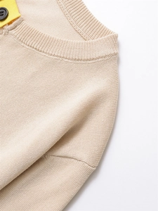 Détail d'un cardigan beige en maille avec col rond côtelé et bordure contrastée jaune à bouton