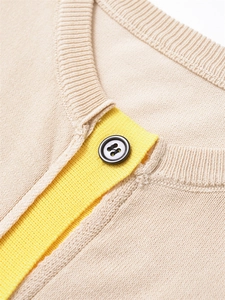 Gros plan d'un cardigan en maille beige avec bordure jaune contrastée et bouton gris foncé