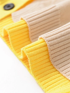 Vue détaillée de la maille jaune et beige avec poignets côtelés et bouton noir mat élégant