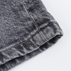 Detalle de shorts vaqueros gris oscuro con costuras de contraste marrón en el dobladillo