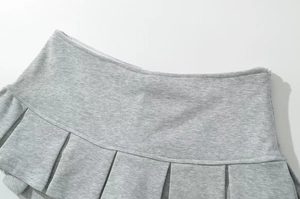 Détail d'une jupe plissée gris clair montrant la texture douce et les coutures de taille