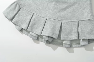 Gros plan d'une jupe plissée gris clair montrant la texture du tissu en maille de qualité