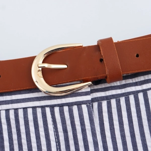 Λεπτομέρεια καφέ δερμάτινης ζώνης με χρυσή αγκράφα πέταλο σε ριγέ παντελόνι