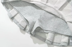 Détail de la mini-jupe plissée gris clair avec short intérieur intégré et maille tricot