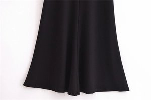 Detailed close-up of the smooth black flared hemline and fabric texture of the dress