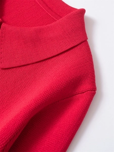 Gros plan détaillé sur la texture tricotée rouge vif et le col de ce pull élégant