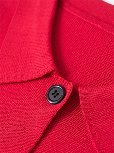 Détail d'un cardigan en maille rouge avec un col à revers et un bouton noir