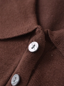 Detailansicht dunkelbrauner Strickpullover mit grauen Perlmuttknöpfen und feiner Textur
