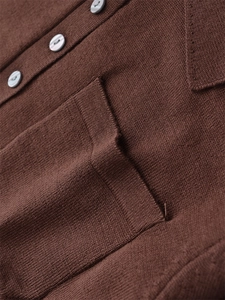 Detailansicht der Strickstruktur mit eleganten grauen Knöpfen und Brusttasche am Pullover