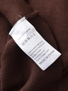 Detail eines braunen Strickpullovers mit 100% Polyester-Pflegeetikett und Textur