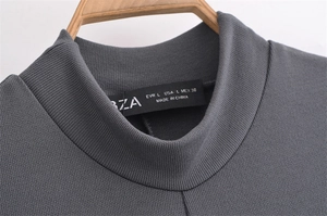 Detail of mock neck collar on dark grey ribbed knit dress with size label on wooden hanger