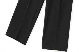 Gros plan du bas d'un pantalon noir avec pli marqué et texture de tissu fluide