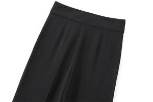 Détail de pantalon noir taille haute montrant les plis avant et la texture du tissu