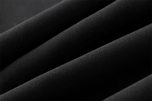 Vue macro d'un tissu crêpe noir montrant un drapé premium et une finition mate
