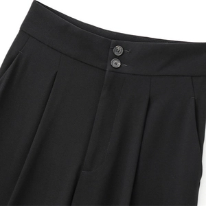 Pantalon noir à taille haute avec plis, double boutonnage et une silhouette drapée fluide