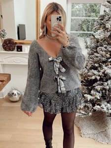 Détail d'un cardigan gris en mohair avec deux grands nœuds en sequins argentés brillants