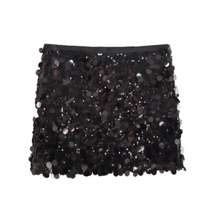 Close-up of black sequined mini skirt fabric showing shiny metallic texture and A-line cut